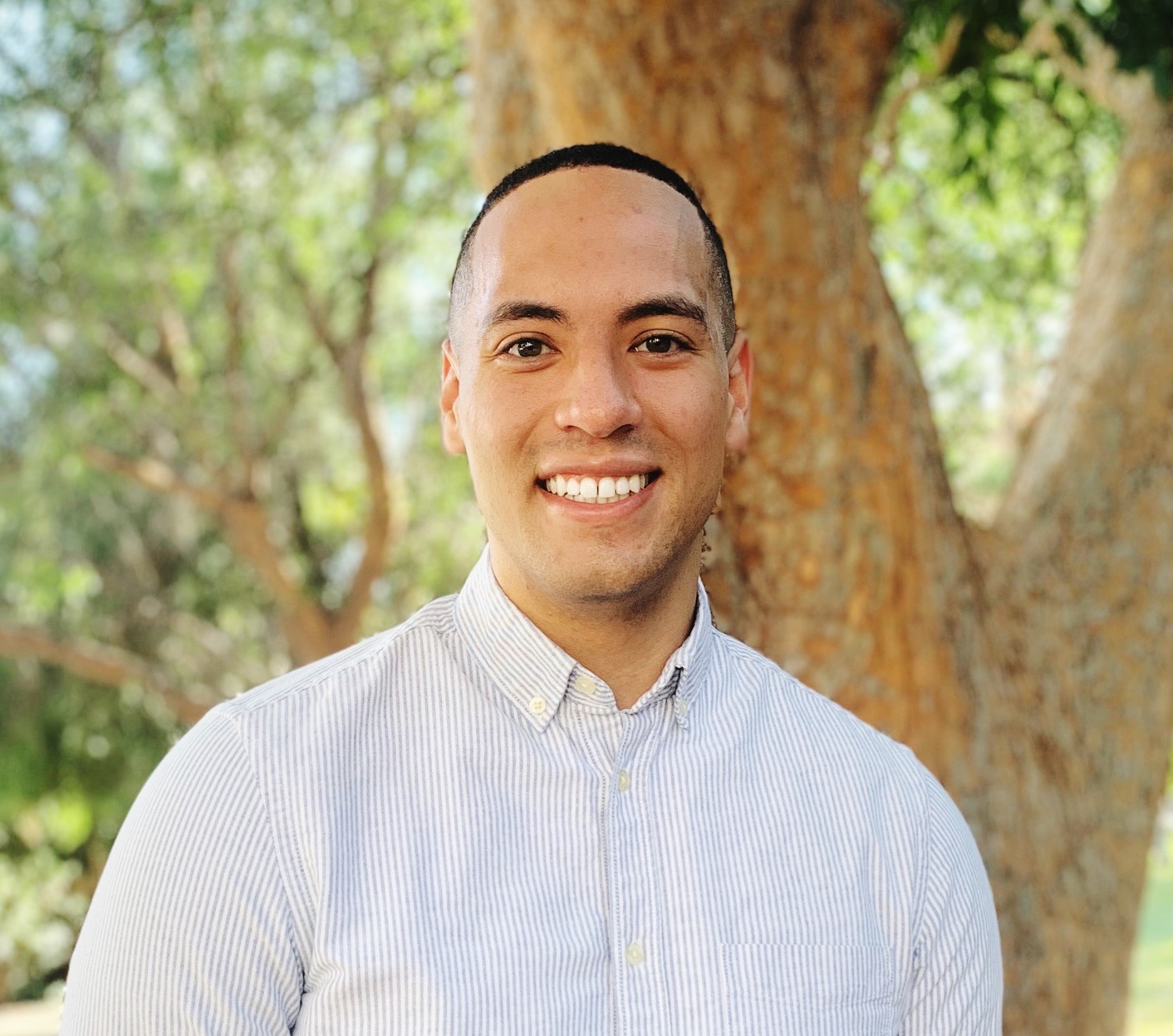 Portrait photo of man looking at camera outdoors.